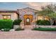 Elegant front entrance with a stone archway, custom iron door, and manicured desert landscaping, radiating sophistication at 11548 E Salero Dr, Scottsdale, AZ 85262