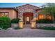 Impressive front entrance with stone archway, custom iron door, and lush landscaping offers a warm welcome at 11548 E Salero Dr, Scottsdale, AZ 85262