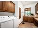 Well-equipped laundry room with side-by-side washer and dryer, custom cabinets, and sink at 11548 E Salero Dr, Scottsdale, AZ 85262