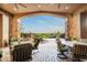 A luxurious covered patio with stone accents, comfortable seating, and views of the refreshing pool and desert landscape at 11548 E Salero Dr, Scottsdale, AZ 85262