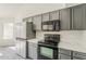 Updated kitchen with stainless steel appliances, gray cabinets, and marble countertops at 15360 N 87Th Ave, Peoria, AZ 85381