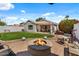 Landscaped backyard with a fire pit area, lush lawn, and covered patio for relaxation and entertaining at 1703 E Palo Blanco Way, Gilbert, AZ 85296