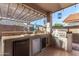 Outdoor kitchen with built-in grill, mini fridge, prep space, and pergola at 18080 W Spencer Dr, Surprise, AZ 85374