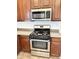 Stainless steel microwave and gas range oven with dark wood cabinets and light countertops at 2539 N 148Th Dr, Goodyear, AZ 85395