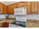 Close up on kitchen with wooden cabinets, granite countertops, and white appliances at 3649 E Hazeltine Way, Chandler, AZ 85249
