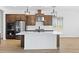 Bright kitchen with a white island, stainless steel appliances, and wood-look floors at 37727 W Padilla St, Maricopa, AZ 85138