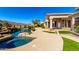 Desert backyard with stone features, green grass, pool, and a covered patio on a sun-drenched day at 402 E Windmere Dr, Phoenix, AZ 85048