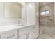 White bathroom with marble tile, a white vanity, and a tub with shower at 402 E Windmere Dr, Phoenix, AZ 85048