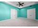 Turquoise bedroom with a ceiling fan, white trim, and bright carpet at 402 E Windmere Dr, Phoenix, AZ 85048