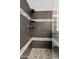 Modern shower design with gray tile, stone floor, built-in shelves and glass door at 4976 E Thunderbird Dr, Chandler, AZ 85249