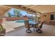 This covered back patio has a table and seating that overlook the sparkling pool at 524 W Sunset Cir, Mesa, AZ 85201