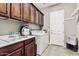 Laundry room with sink, wooden cabinets, and modern washer and dryer at 5541 W Desperado Way, Phoenix, AZ 85083