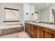 Bathroom featuring double vanities and a soaking tub by a window at 7552 E Whisper Rock Trl, Scottsdale, AZ 85266