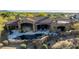 Overhead shot of a stone-clad home with a patio, pool, and lush desert landscaping at 7552 E Whisper Rock Trl, Scottsdale, AZ 85266