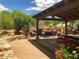 Inviting outdoor patio with stone fireplace, covered seating, and lush landscaping provides a relaxing retreat at 7552 E Whisper Rock Trl, Scottsdale, AZ 85266