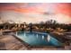 Luxury pool with water features and lush landscaping, set against a colorful evening sky at 7552 E Whisper Rock Trl, Scottsdale, AZ 85266