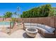 Comfortable backyard seating around a fire pit, with pool and lush plantings nearby at 9345 W Robin Ln, Peoria, AZ 85383
