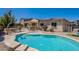 A backyard pool with stone surround, fenced in and landscaped, with covered patio at 9345 W Robin Ln, Peoria, AZ 85383