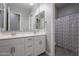Clean bathroom features dual sinks, white cabinets, and a shower/tub with decorative curtain at 9345 W Robin Ln, Peoria, AZ 85383