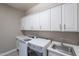Bright laundry room with white cabinets above modern washer and dryer, plus a sink at 9345 W Robin Ln, Peoria, AZ 85383