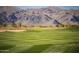 Picturesque golf course view with manicured greens, sand trap, and mountain views in the background at 11300 N Casa Dega Dr # 1019, Surprise, AZ 85388