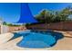 Backyard pool with shade cover and waterfall feature, surrounded by lush landscaping and brick wall at 12601 W San Miguel Ave, Litchfield Park, AZ 85340