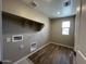 Practical laundry room featuring wooden tile flooring, shelving, and connections for a washer and dryer at 17493 W Fulton St, Goodyear, AZ 85338