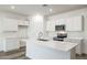 Modern kitchen with stainless steel appliances, an island, white cabinets, and wood-look floors at 17778 W Turquoise Ave, Waddell, AZ 85355