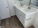 Bathroom with double sinks, white cabinets, and wood-style flooring at 18361 W Jessie Ln, Surprise, AZ 85387