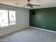 Bedroom with a ceiling fan, green wall, and window overlooking the neighborhood at 18361 W Jessie Ln, Surprise, AZ 85387