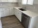 Bright kitchen showcasing white cabinets, stainless steel dishwasher, and wood-look tile flooring at 18361 W Jessie Ln, Surprise, AZ 85387