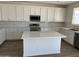 Kitchen featuring white cabinets, a large island, stainless steel appliances and wood-look tile flooring at 18361 W Jessie Ln, Surprise, AZ 85387