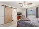 Main bedroom boasts a barn door to the en suite bath, a TV and ample natural light from the sliding glass window at 22578 E Sahara Dr, Florence, AZ 85132