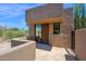 Contemporary home exterior featuring a desert landscape and a walled stone patio with glass front door at 35180 N Boulder Pass, Scottsdale, AZ 85266