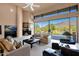 Living room with fireplace and pool view, showcasing a comfortable seating arrangement with a mountain backdrop at 35180 N Boulder Pass, Scottsdale, AZ 85266