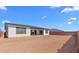 View of spacious backyard featuring neutral stucco exterior with dark trim windows and covered patio at 37735 W Santa Maria St, Maricopa, AZ 85138