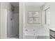 Bright bathroom featuring a walk-in shower with glass door and separate soaking tub by the window at 3837 E Santa Fe Ln, Gilbert, AZ 85297