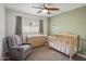 Cozy Bedroom with a gray recliner, wooden crib and changing table, and neutral carpet at 502 W Port Royale Ln, Phoenix, AZ 85023