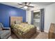 Bedroom with a wood frame bed, an accent blue wall, a ceiling fan, and a window with curtains at 502 W Port Royale Ln, Phoenix, AZ 85023