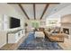 Spacious living room with exposed beam ceiling, fireplace, and cozy brown sectional couch at 502 W Port Royale Ln, Phoenix, AZ 85023