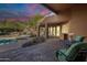 Inviting pool area with covered patio, fireplace and comfortable seating under sunset at 5892 E Carefree Mountain Dr, Carefree, AZ 85377