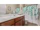 Bathroom with wood cabinets, white counter, sink, and shower with floral curtain at 729 W Silver Reef Dr, Casa Grande, AZ 85122