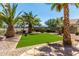 Landscaped backyard with palm trees and artificial turf for easy maintenance and enjoyment at 7365 W Magdalena Ln, Laveen, AZ 85339