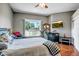 Relaxing bedroom with large window view, ceiling fan, TV, and hardwood floors at 10643 W Pineaire W Dr, Sun City, AZ 85351