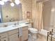 Clean bathroom with white vanity, toilet, and shower-tub combo, all adorned with vintage wallpaper at 1118 E Orangewood Ave, Phoenix, AZ 85020