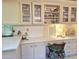 Bright kitchen featuring off-white cabinets, glass-front displays, and a cozy built-in desk area with a chair at 1118 E Orangewood Ave, Phoenix, AZ 85020