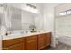 Bathroom with dual sink vanity and white-tiled shower and tub at 11182 W Coronado Rd, Avondale, AZ 85392