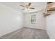A bright bedroom with neutral carpet, ceiling fan, and shelving. A sunlit window adds warmth at 12531 W Glenn Dr, Glendale, AZ 85307