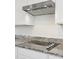 Modern kitchen featuring granite countertops and a sleek cooktop with stainless steel vent hood at 12531 W Glenn Dr, Glendale, AZ 85307