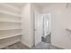 Spacious walk-in closet with built-in shelving and neutral carpeting adjacent to the bathroom at 12531 W Glenn Dr, Glendale, AZ 85307